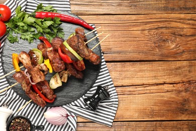 Photo of Delicious shish kebabs with vegetables and spices on wooden table, flat lay. Space for text