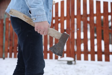 Man with metal axe outdoors on winter day, closeup. Space for text