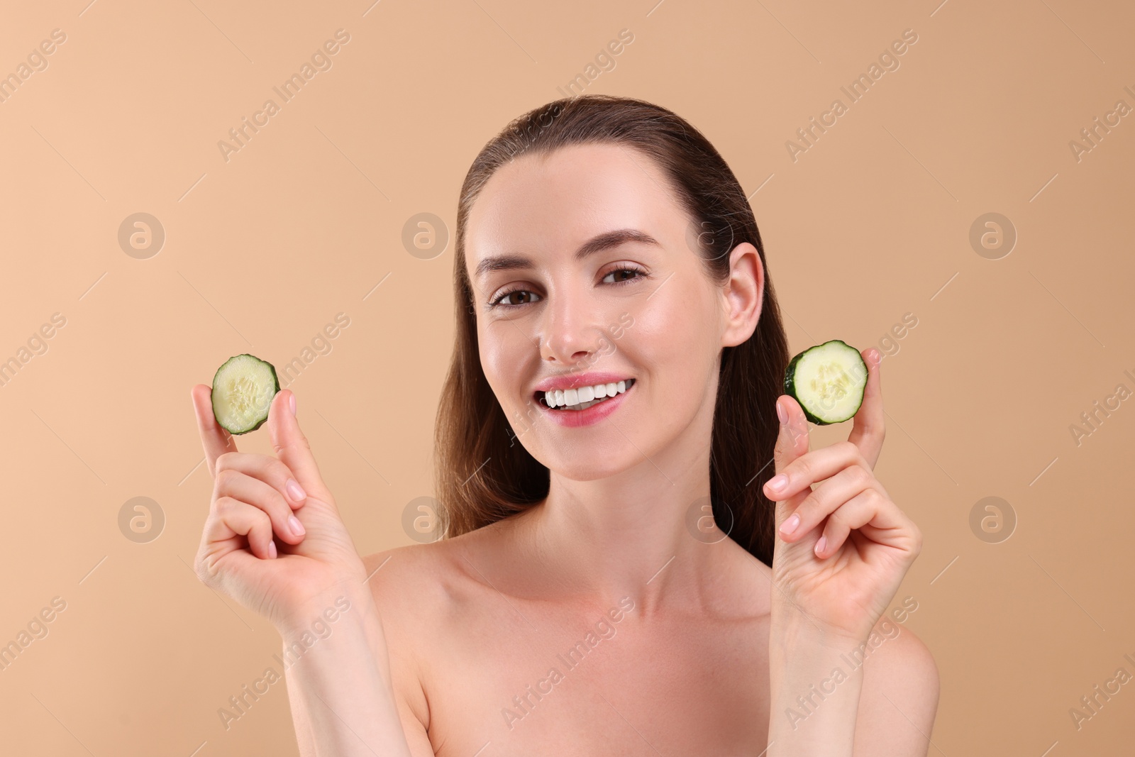 Photo of Beautiful woman with pieces of cucumber on beige background