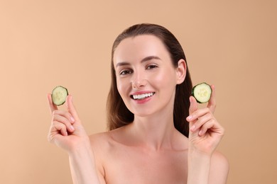Beautiful woman with pieces of cucumber on beige background