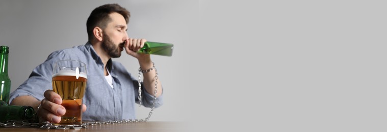 Image of Suffering from hangover. Man chained with alcoholic drink at table against white background, space for text. Banner design