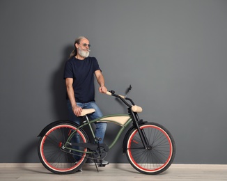 Portrait of handsome mature man with bicycle near color wall