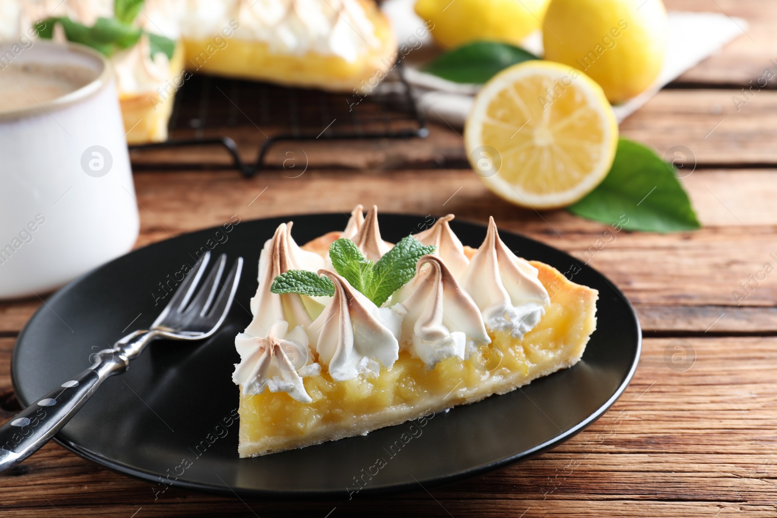 Photo of Piece of delicious lemon meringue pie served on wooden table