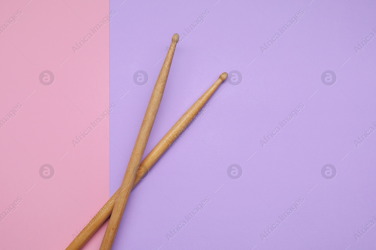 Photo of Two wooden drum sticks on color background, top view. Space for text