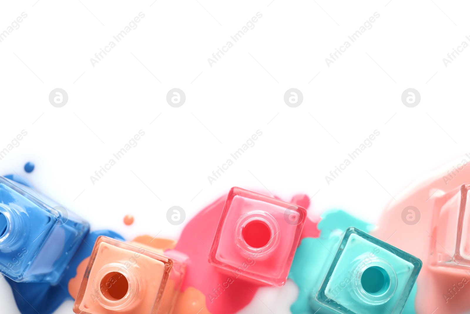 Photo of Spilled different nail polishes with bottles on white background, top view