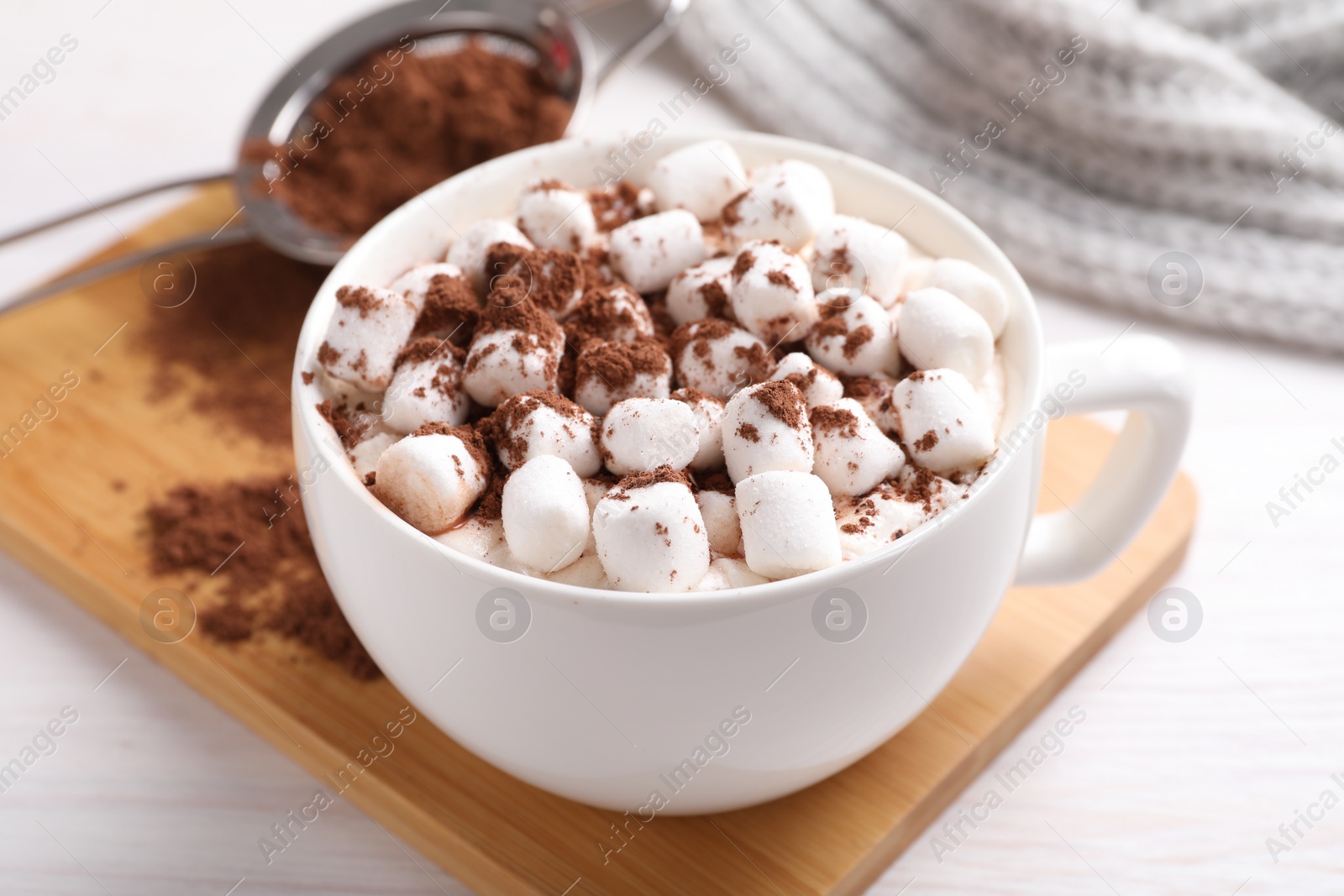 Photo of Cup of aromatic hot chocolate with marshmallows and cocoa powder on table, closeup