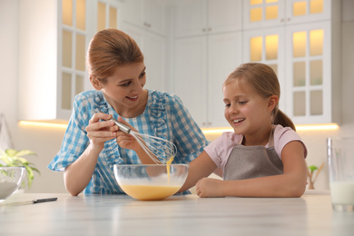 Photo of Mother and daughter making dough together in kitchen