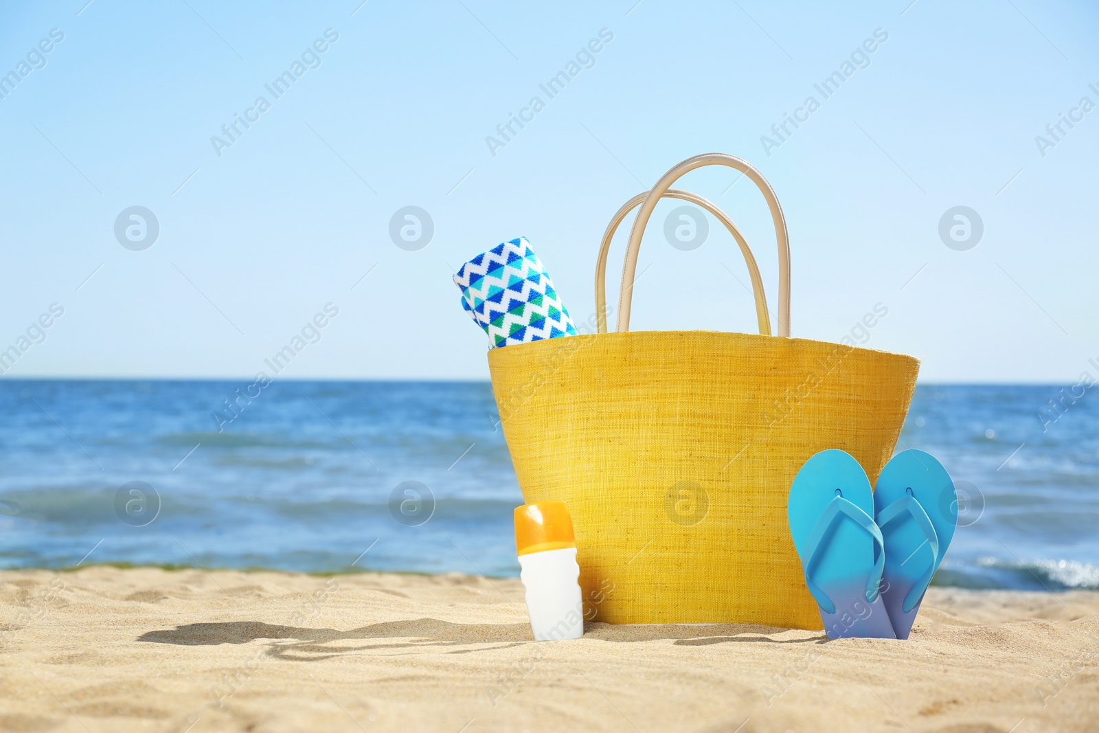 Photo of Stylish beach accessories on sand near sea. Space for text