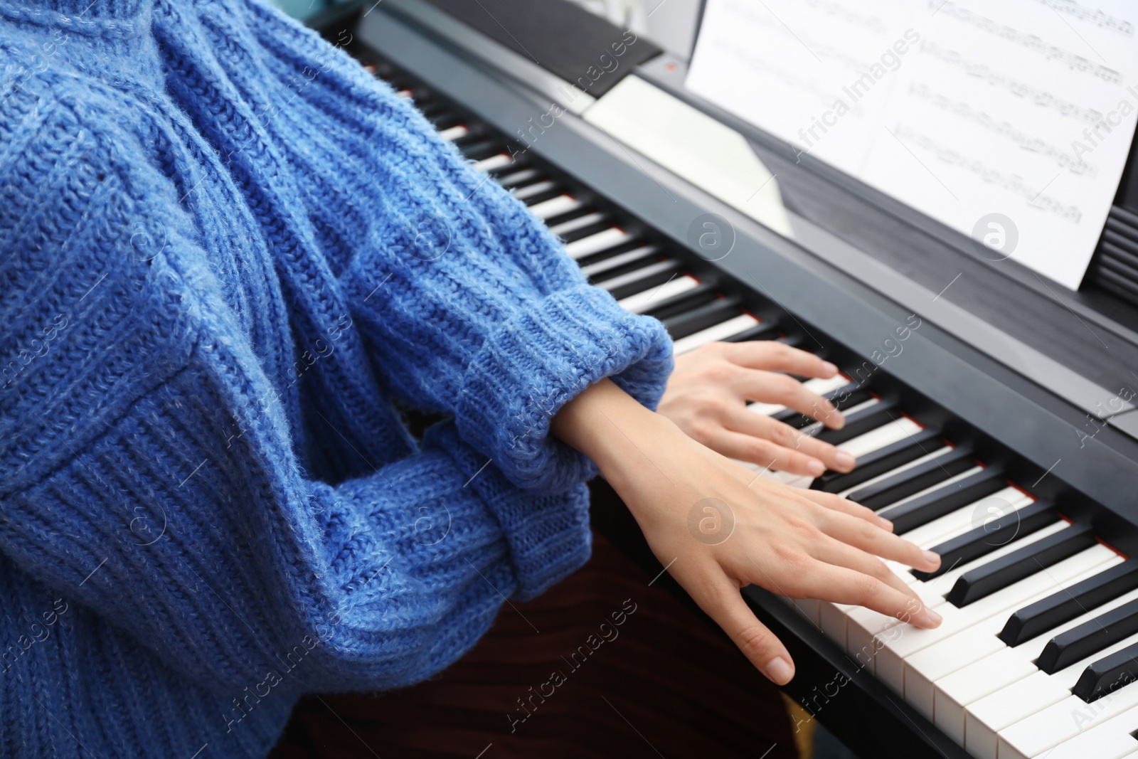 Photo of Young woman playing piano at home, closeup