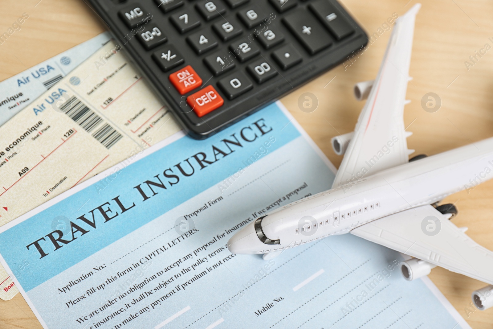 Photo of Composition with toy plane, calculator and travel insurance form on table