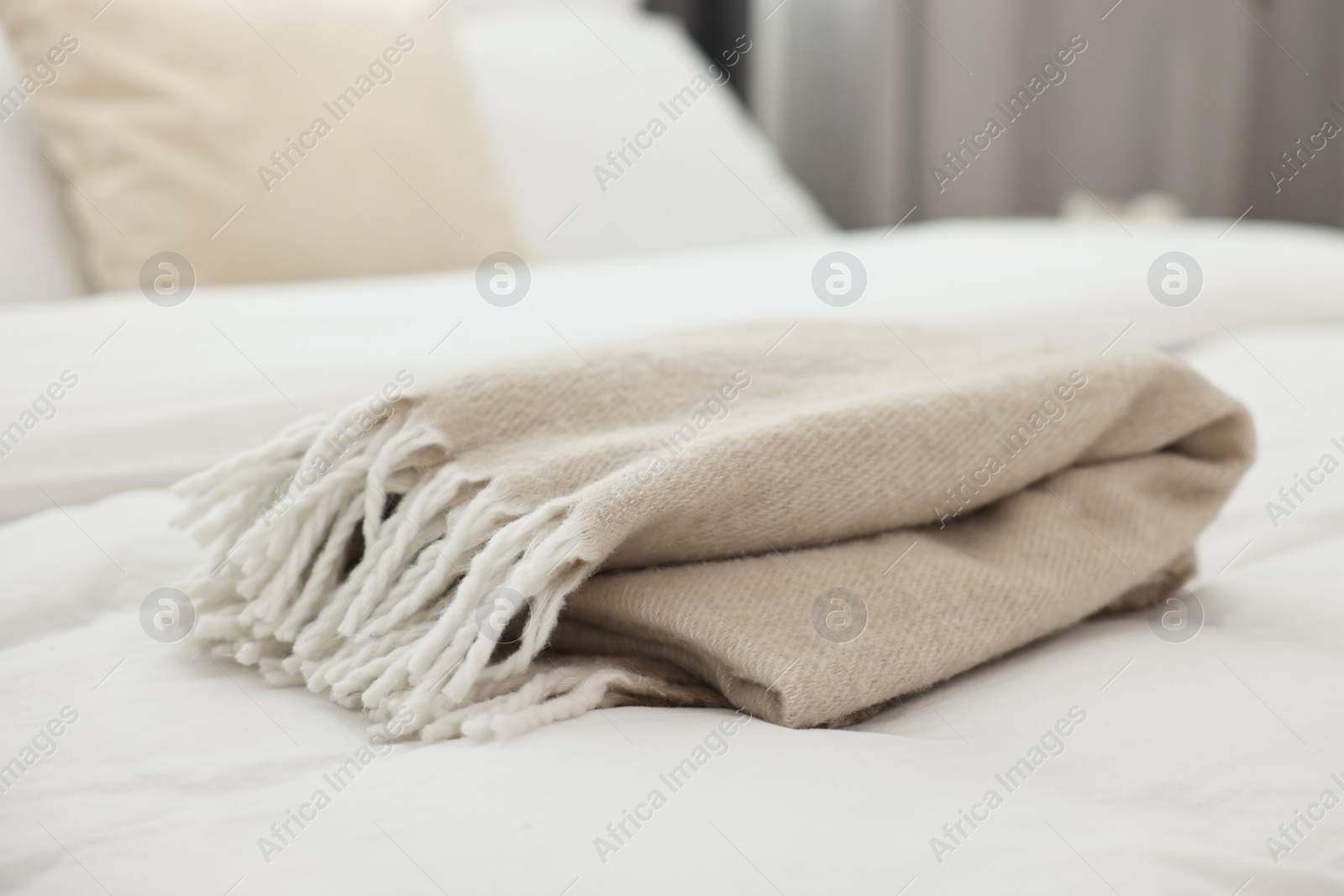 Photo of Soft beige plaid on bed in bedroom