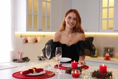 Photo of Beautiful young woman setting table for Christmas celebration in kitchen