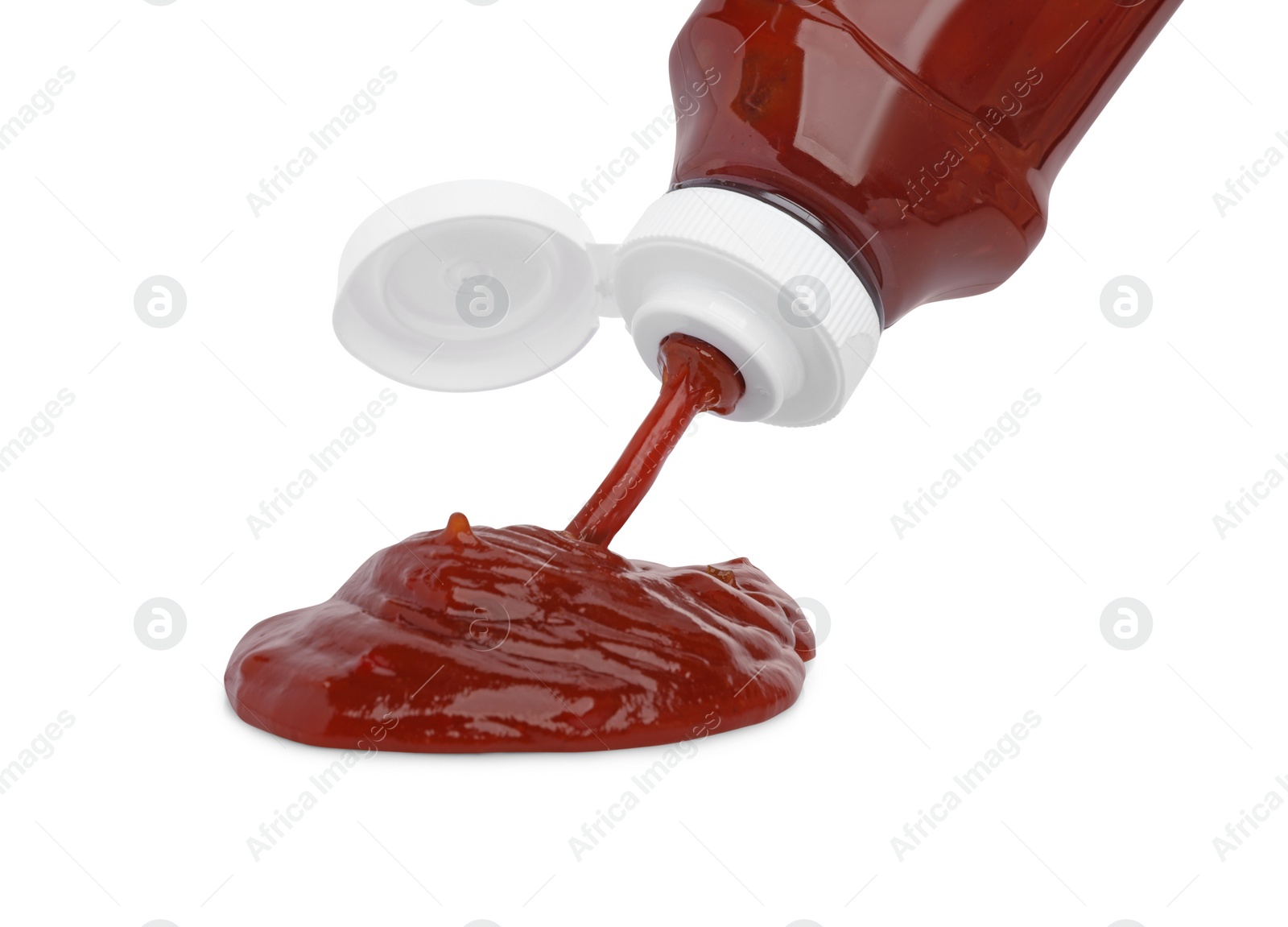 Photo of Pouring tasty red ketchup from bottle isolated on white