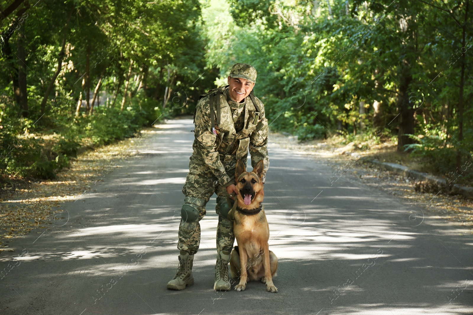 Photo of Man in military uniform with German shepherd dog outdoors