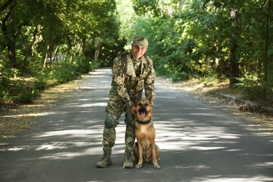 Photo of Man in military uniform with German shepherd dog outdoors