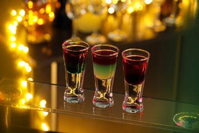 Photo of Different shooters in shot glasses on surface against blurred background Alcohol drink
