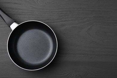 Photo of One frying pan on grey wooden table, top view. Space for text
