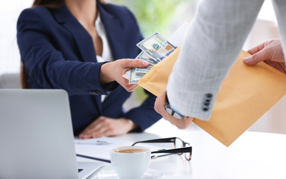 Man giving bribe to woman at table in office, closeup