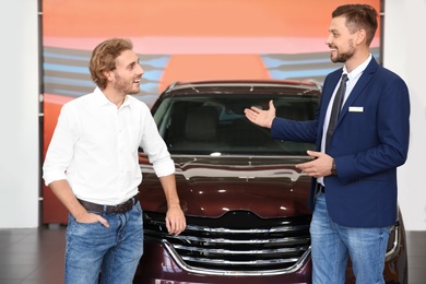 Photo of Salesman with customer in modern car dealership