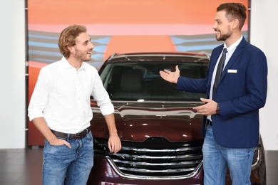 Salesman with customer in modern car dealership