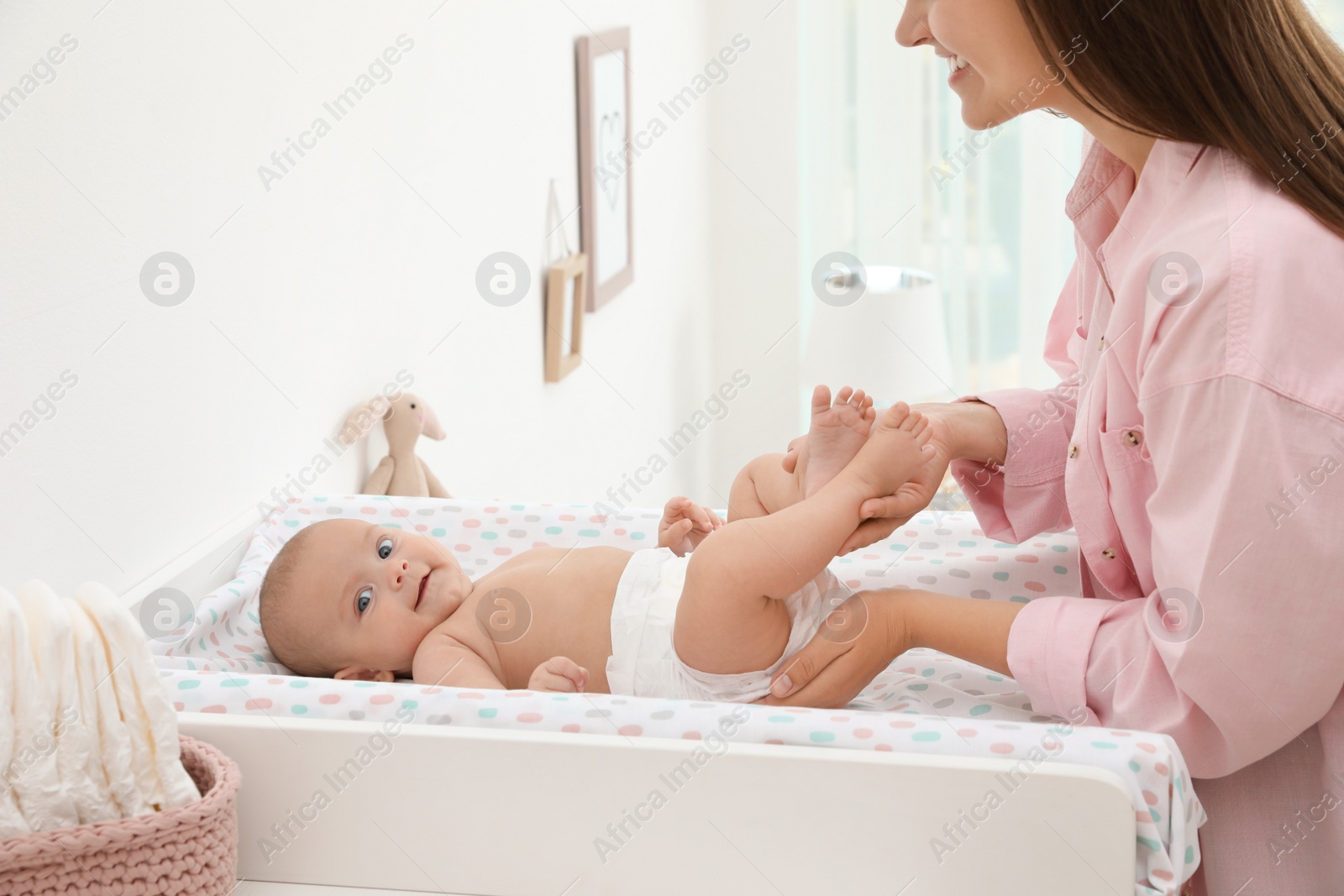 Photo of Mother changing her baby's diaper on table at home