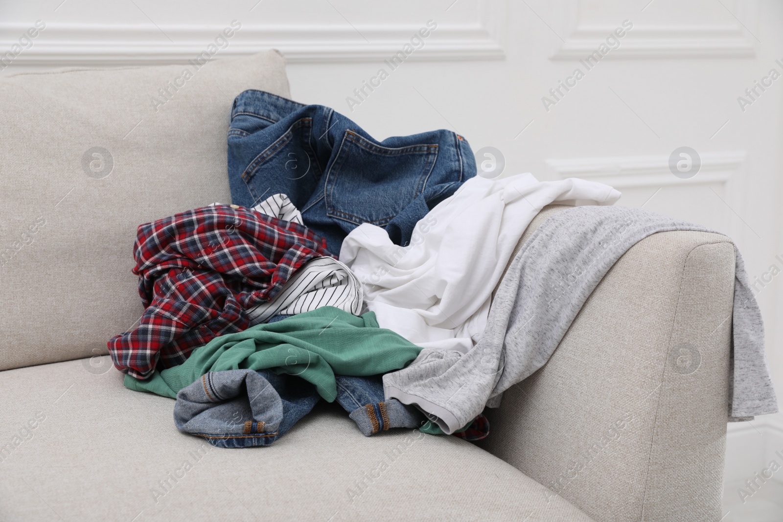 Photo of Pile of dirty clothes on sofa in living room