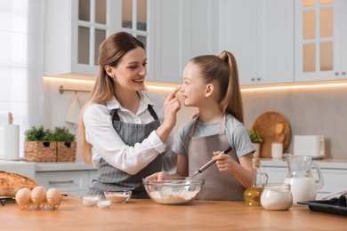 Making bread. Mother and her daughter preparing dough at wooden table in kitchen