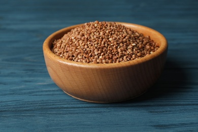 Uncooked buckwheat in bowl on wooden table