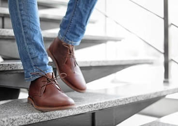 Man in in elegant shoes walking down stairs indoors