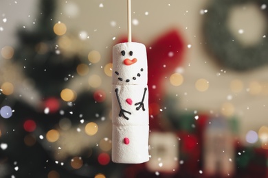 Funny snowman made of marshmallows against blurred Christmas tree, closeup