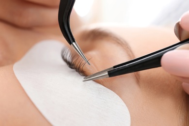 Young woman undergoing eyelash extensions procedure, closeup