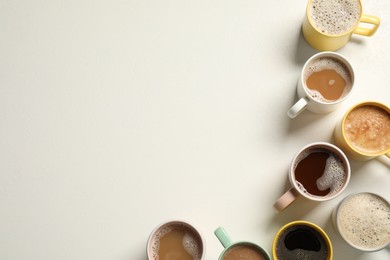 Photo of Many cups with different aromatic coffee on white table, flat lay. Space for text