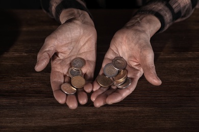 Poor mature woman holding coins at table