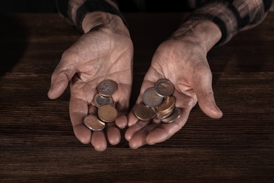 Photo of Poor mature woman holding coins at table