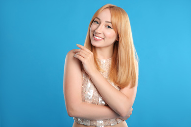 Portrait of beautiful young woman with blonde hair on blue background