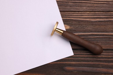 One stamp tool and sheet of paper on wooden table, top view. Space for text