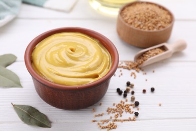 Photo of Bowl with delicious mustard and seeds on white wooden table, closeup. Space for text