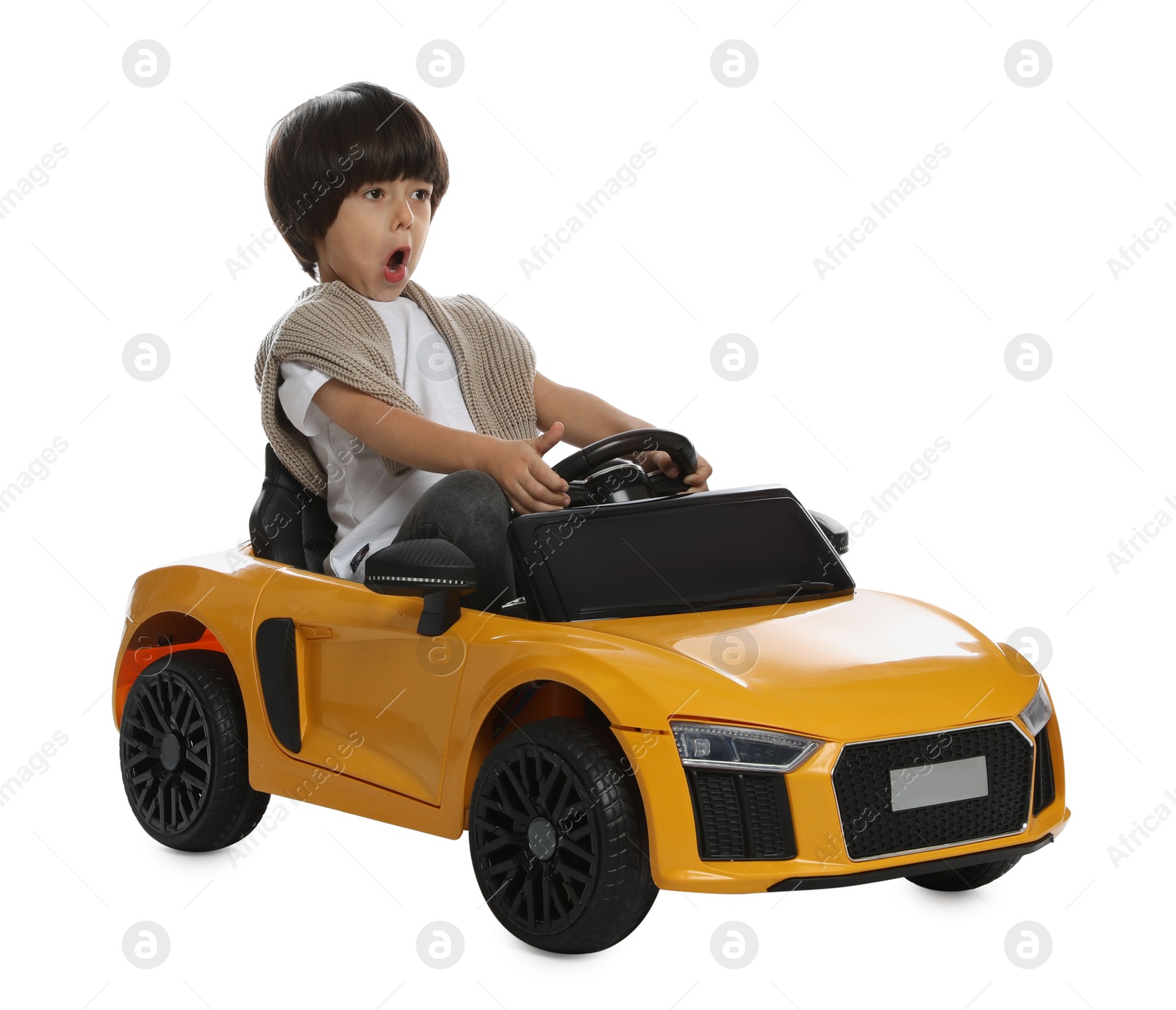 Photo of Cute little boy driving children's electric toy car on white background