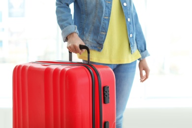 Young woman with suitcase indoors