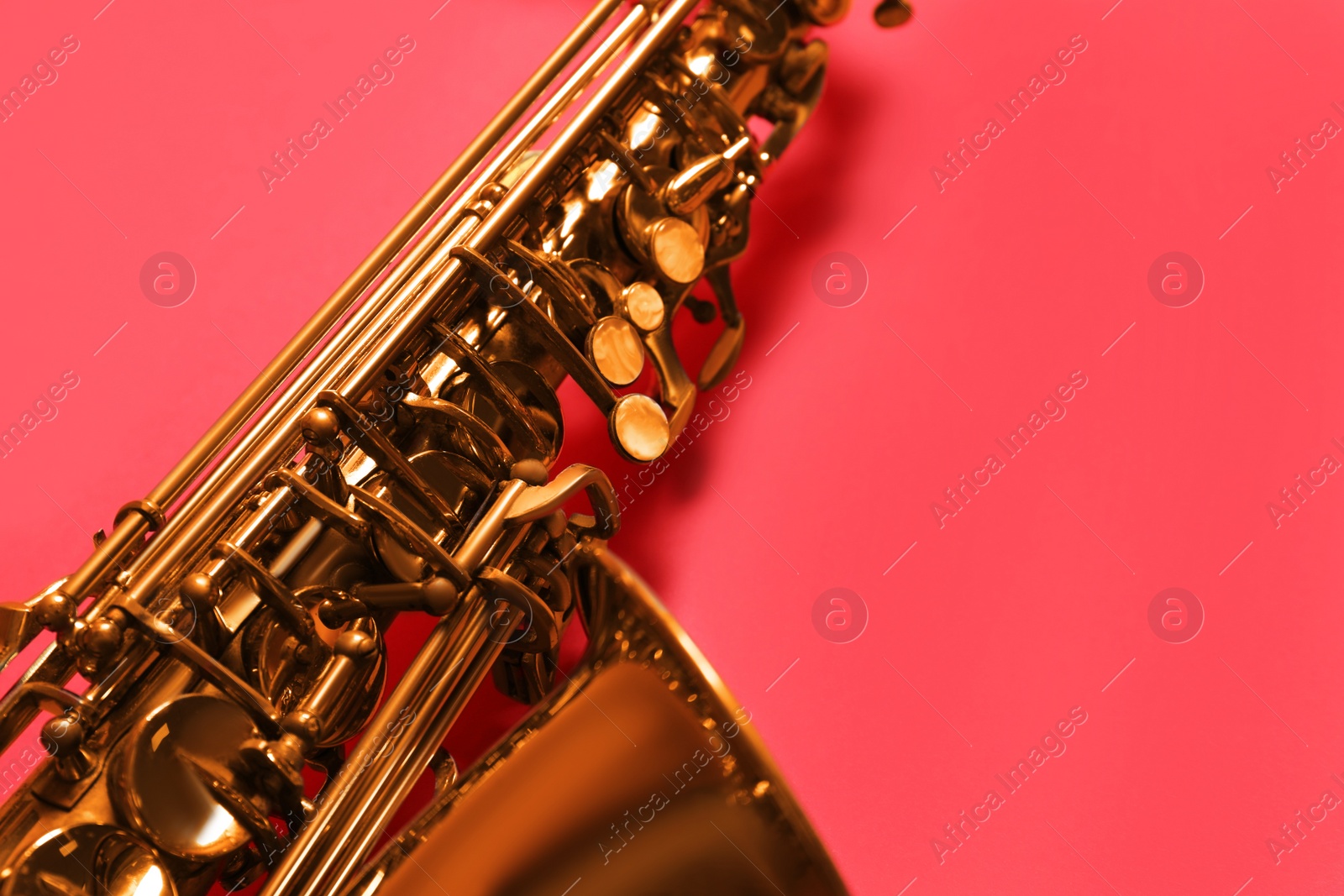 Photo of Beautiful saxophone on red background, closeup view