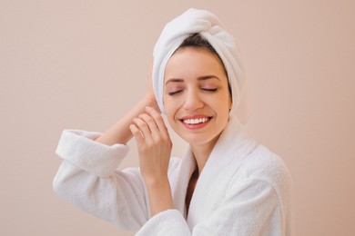 Photo of Beautiful young woman with hair wrapped in towel after washing on beige background