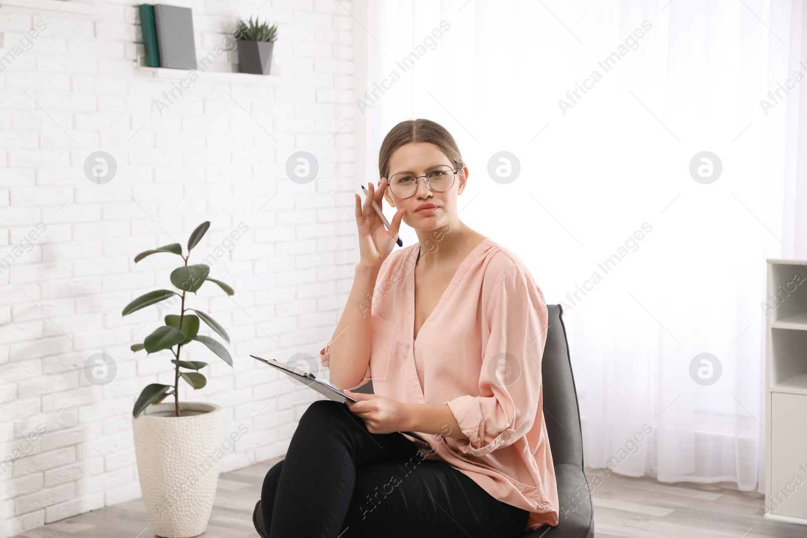 Photo of Professional psychotherapist with clipboard in modern office