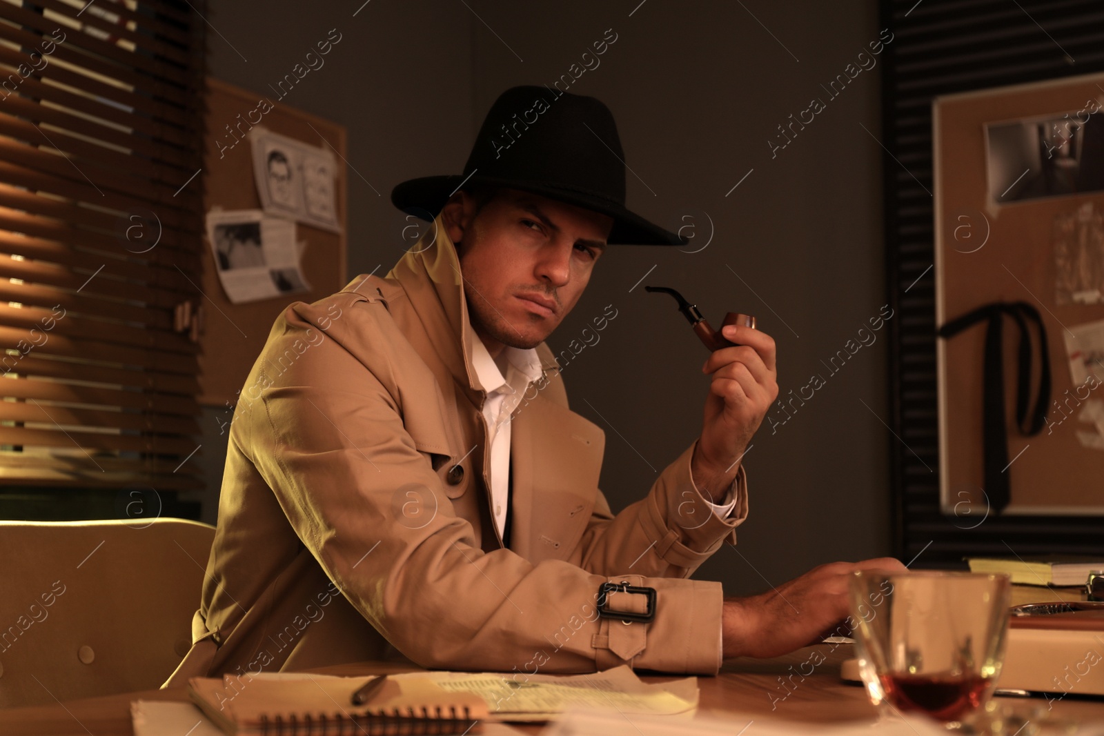 Photo of Old fashioned detective with smoking pipe using typewriter at table in office