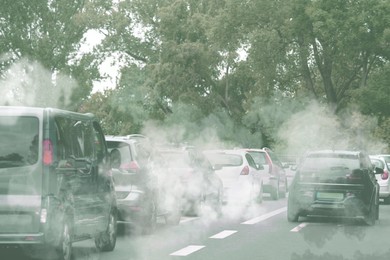 Image of Environmental pollution. Air contaminated with fumes in city. Cars surrounded by exhaust on road