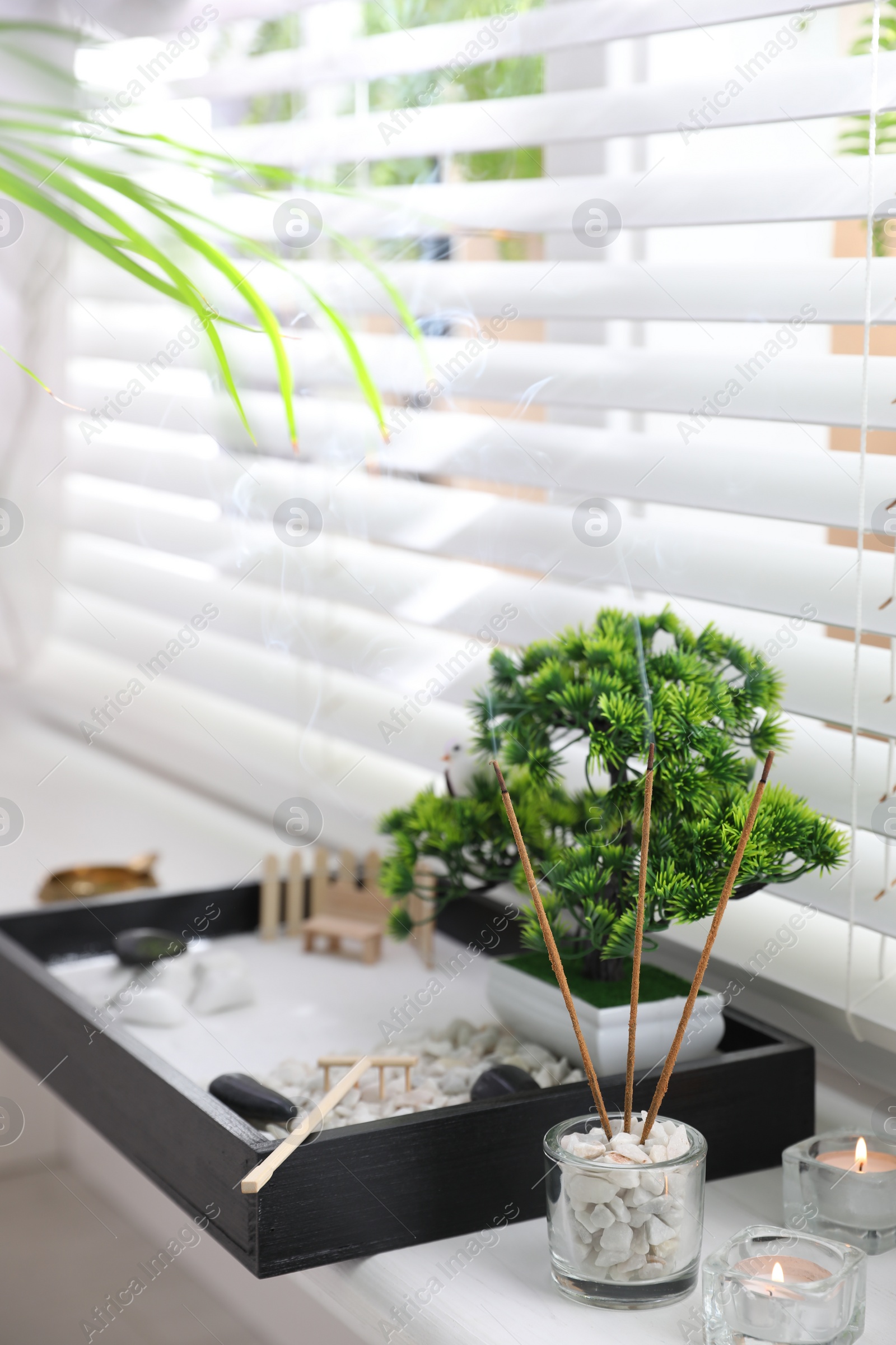 Photo of Beautiful miniature zen garden, candles and incense sticks on window sill