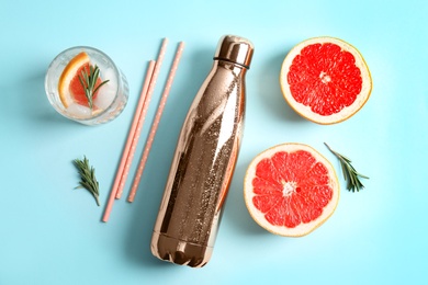 Flat lay composition with glass of infused water, grapefruits and bottle on color background