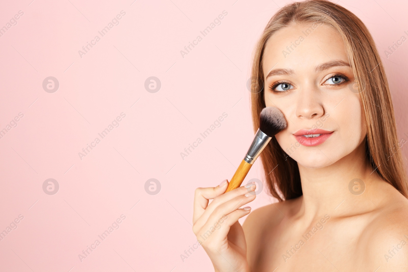 Photo of Portrait of beautiful young woman with makeup brush on color background. Space for text