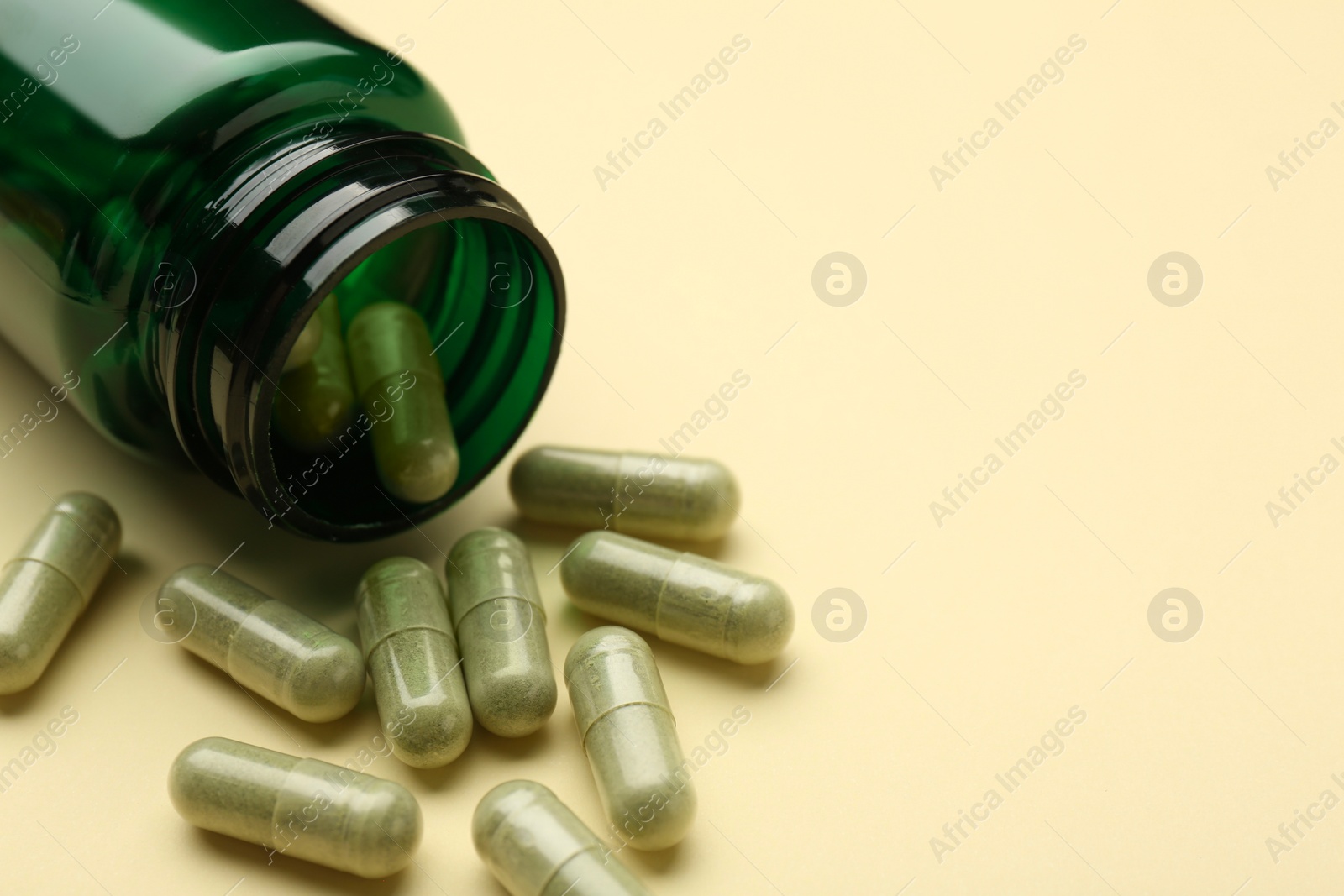 Photo of Vitamin pills and bottle on beige background, closeup. Space for text