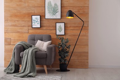 Photo of Stylish room interior with floor lamp, beautiful paintings and potted eucalyptus plant