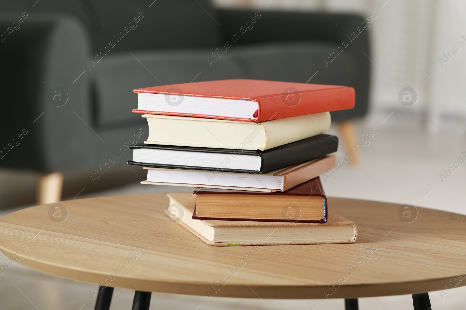 Photo of Stack of different hardcover books on wooden table indoors